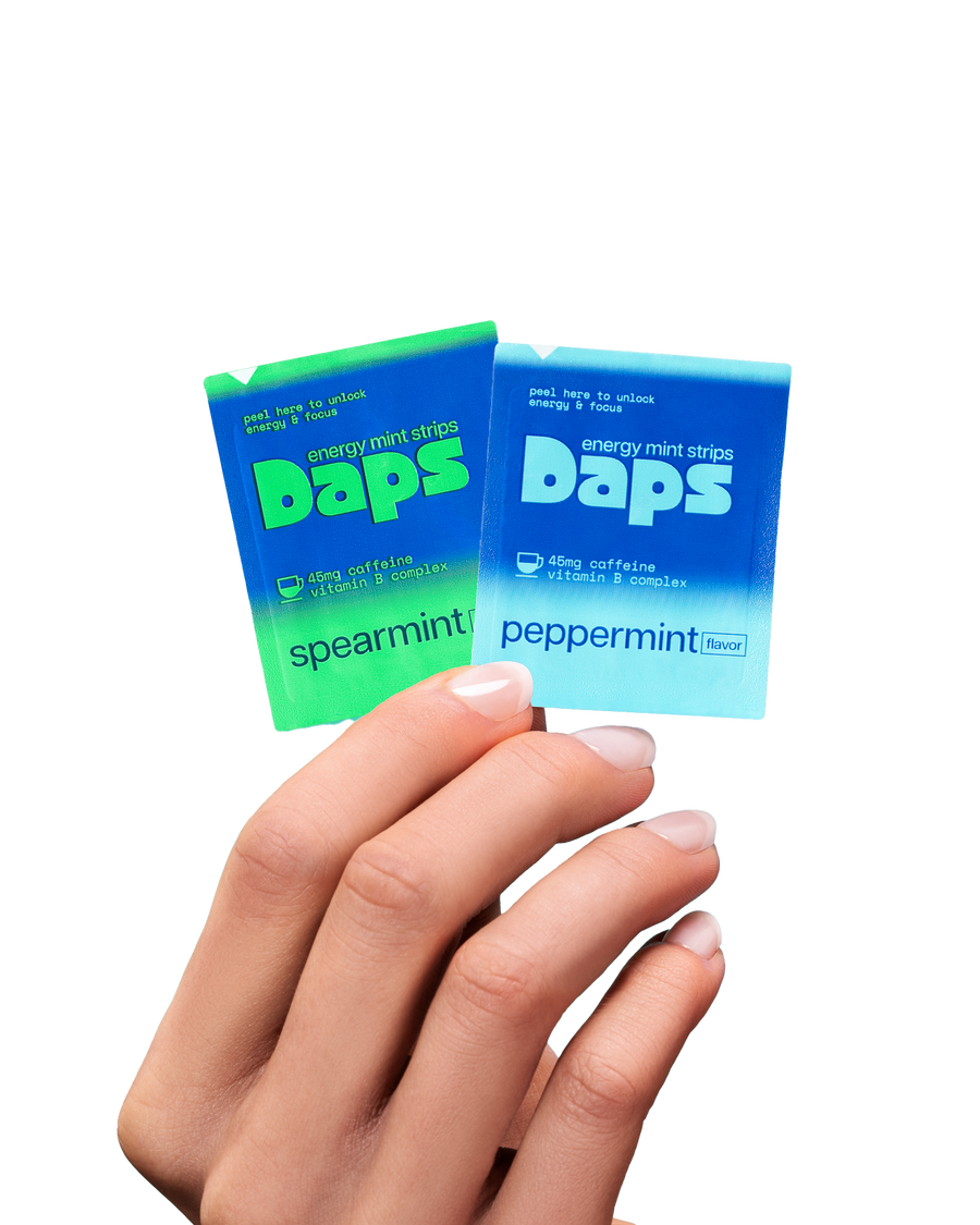 Hand holding two Daps energy mint strips sachets, one spearmint and one peppermint